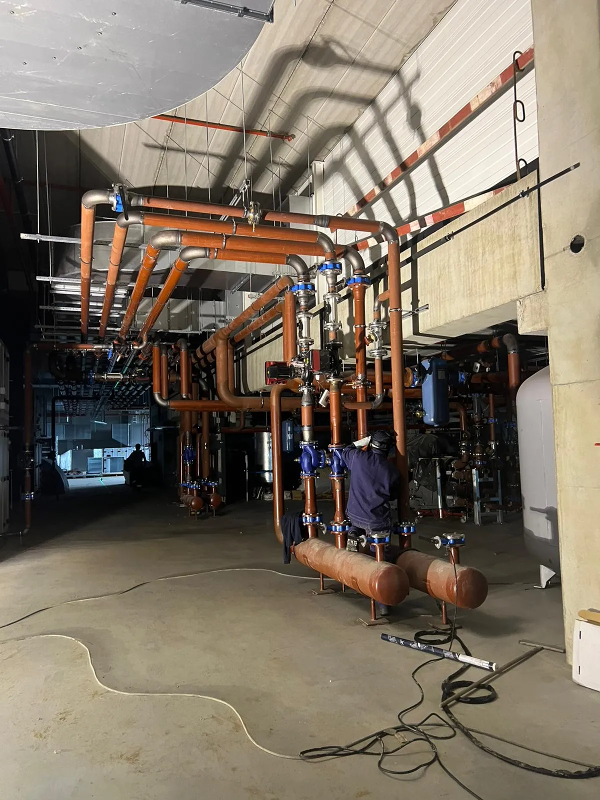 Industrial HVAC pipework installation with copper pipes, valves and a fitter at work
